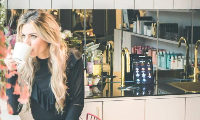 Woman enjoying a TopBrewer coffee next to a TopBrewer with gold swan neck