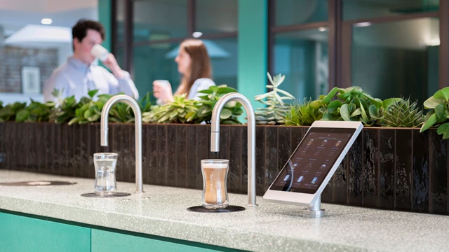 Image showing a TopBrewer commercial coffee machine and TopWater water dispenser with two people chatting in the background