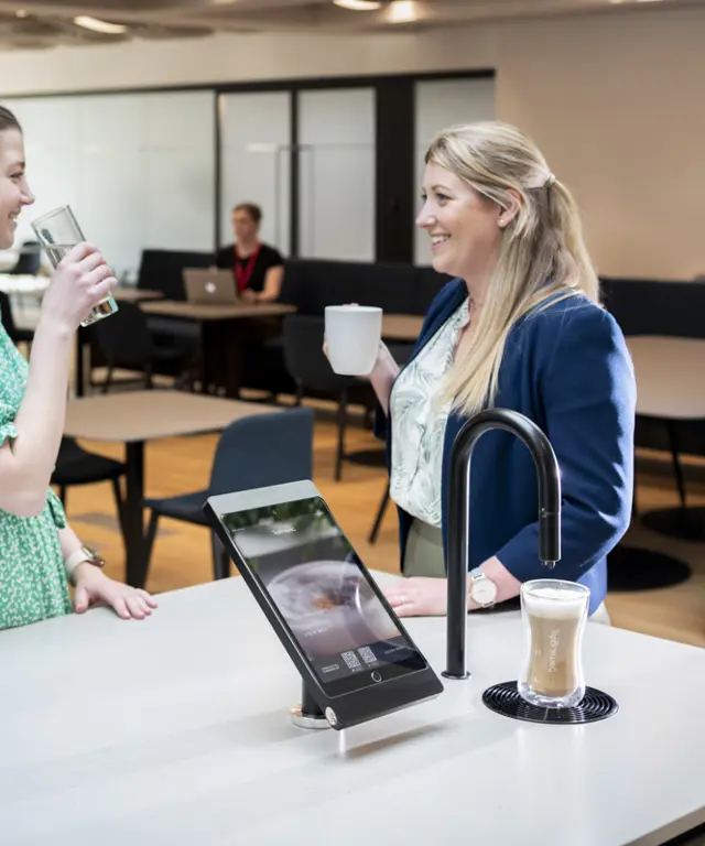 Image showing two people chatting next to a matte black TopBrewer with deluxe iPad holder