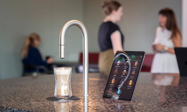 Image showing TopBrewer commercial coffee machine in the foreground with people chatting and working on laptops in the background