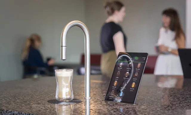 Image showing TopBrewer commercial coffee machine in the foreground with people chatting and working on laptops in the background