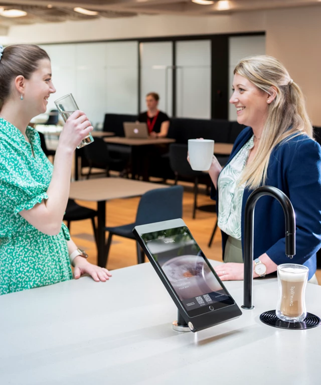Image showing two people chatting next to a matte black TopBrewer with deluxe iPad holder