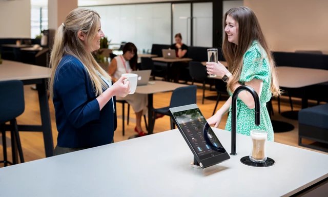 Image showing matte black TopBrewer with deluxe iPad holder and two people chatting next to it